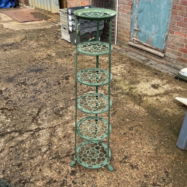 Vintage green metal pan stand with six ornate shelves.
