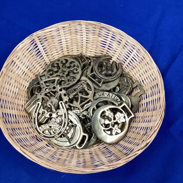 Basket of vintage horse brasses, antique equestrian ornaments.