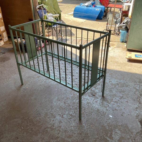Vintage metal crib with wire spring base, side view.