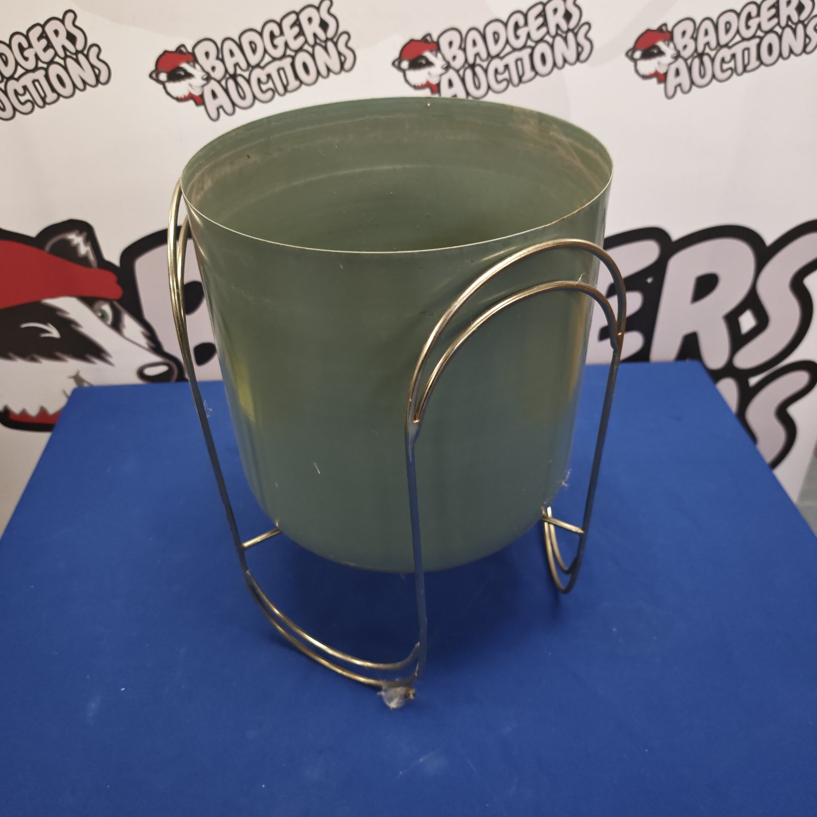 Vintage metal planter with green pot and wire handle.