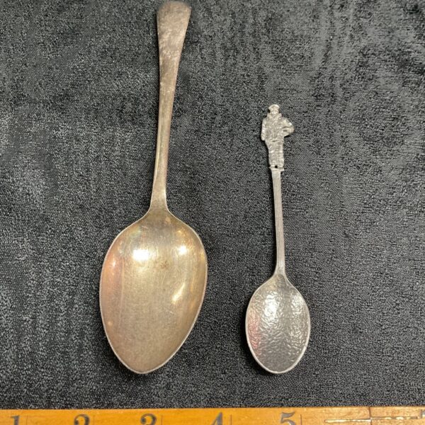 Pair of antique silver plated military spoons on dark fabric.