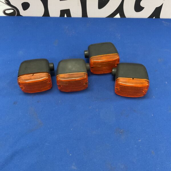 Vintage motorcycle turn signal with clear orange lens.