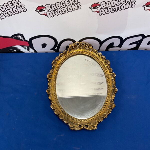 Vintage oval gilt mirror with ornate gold frame.