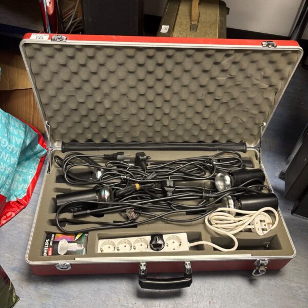 Open red transit case revealing vintage photography lighting kit.
