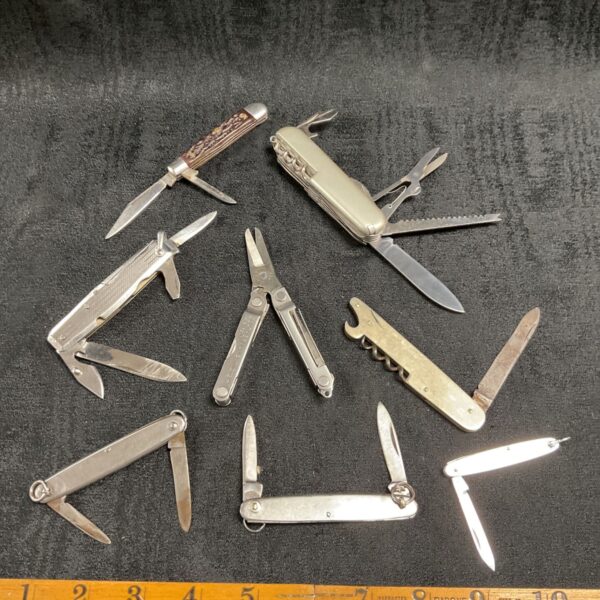 Vintage pocket knife collection with multiple folding knives displayed.