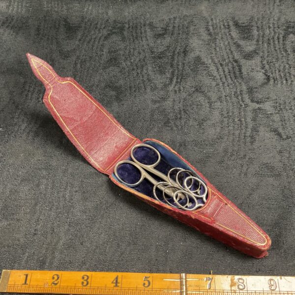Vintage scissor set in a burgundy leather box, antique sewing tools.
