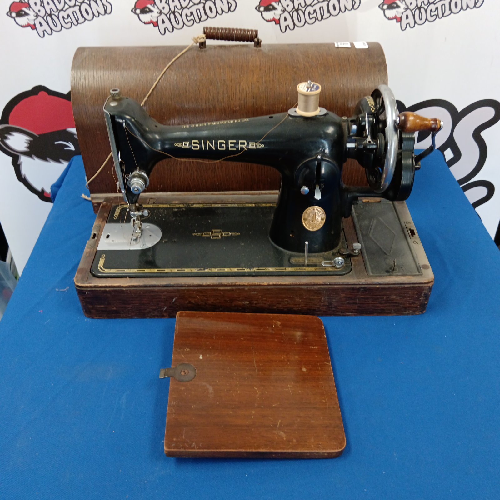 Vintage Singer sewing machine with wooden base and hand crank.