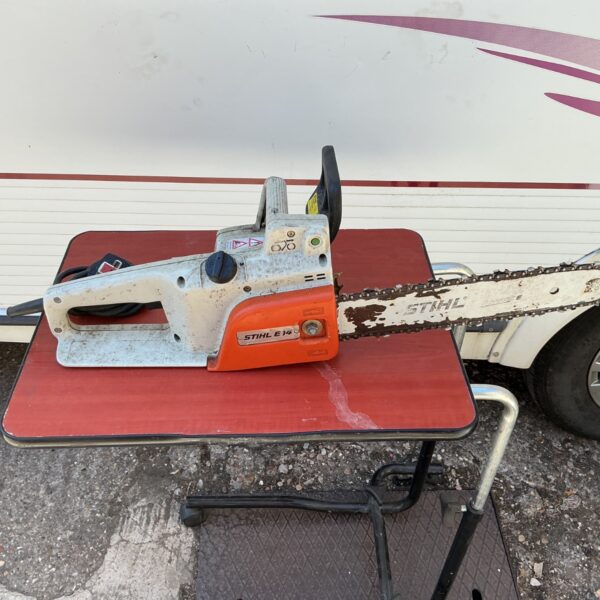 Vintage Stihl E14 electric chainsaw on a workbench.