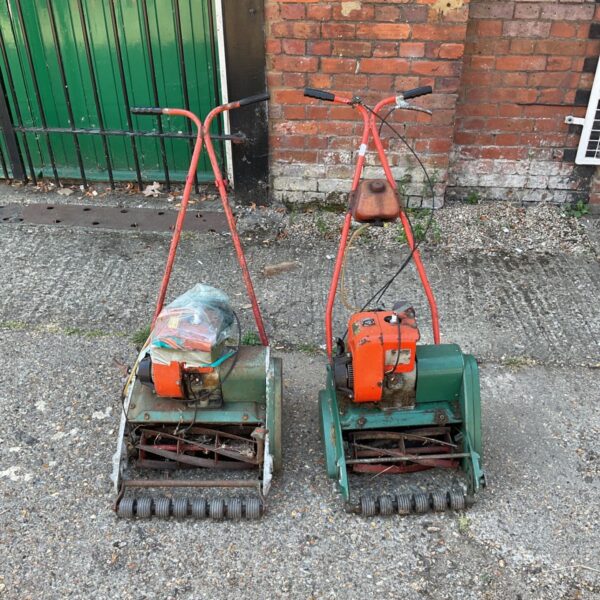Pair of vintage Suffolk Punch lawnmowers in a garden setting.