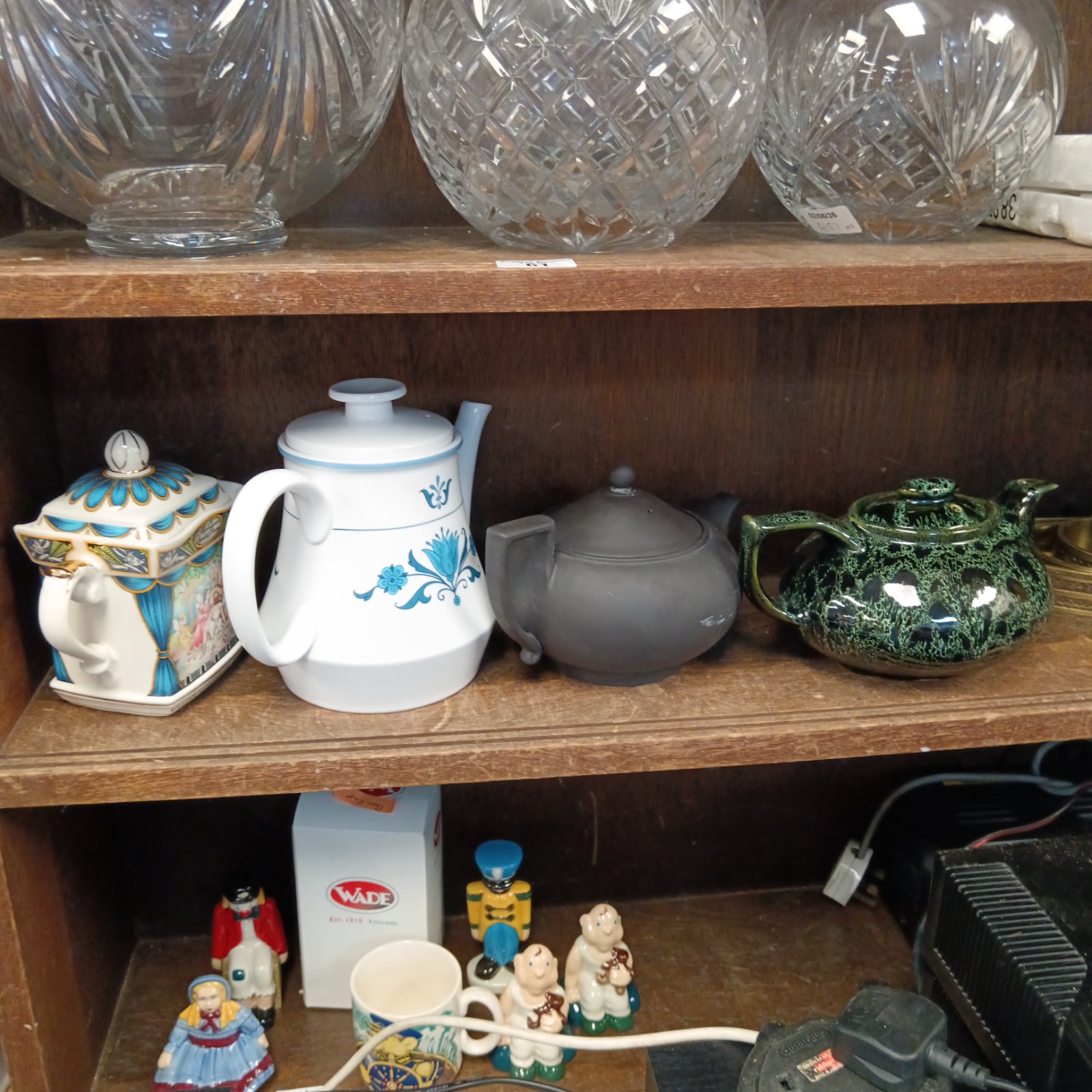 A shelf displaying a collection of vintage and collectable teapots.