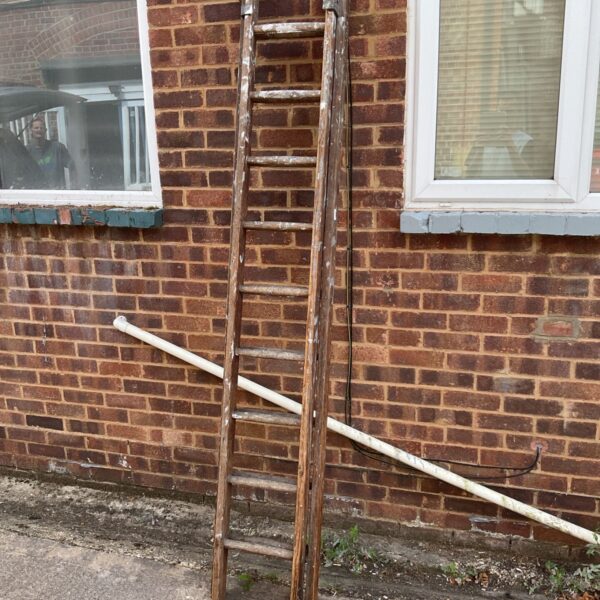 Vintage wooden ladder leaning against brick wall.