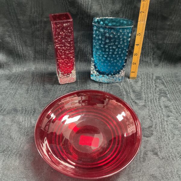 Whiefriars glass collection featuring a red bowl and blue vase.