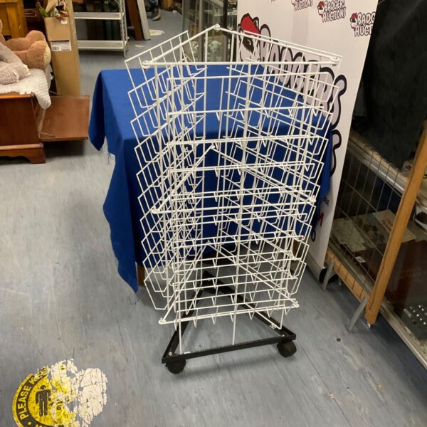 White metal magazine rack with tiered design and wheels.