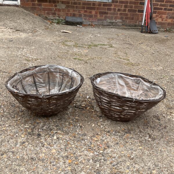 Two rustic wicker hanging baskets for garden plants.