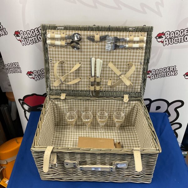 Open wicker picnic basket filled with plates, cutlery, and glasses.