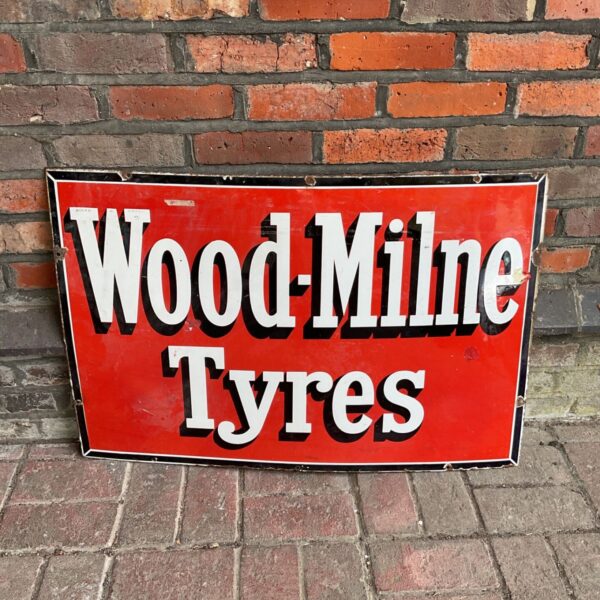 Vintage Wood Milne Tyres enamel sign with red background.