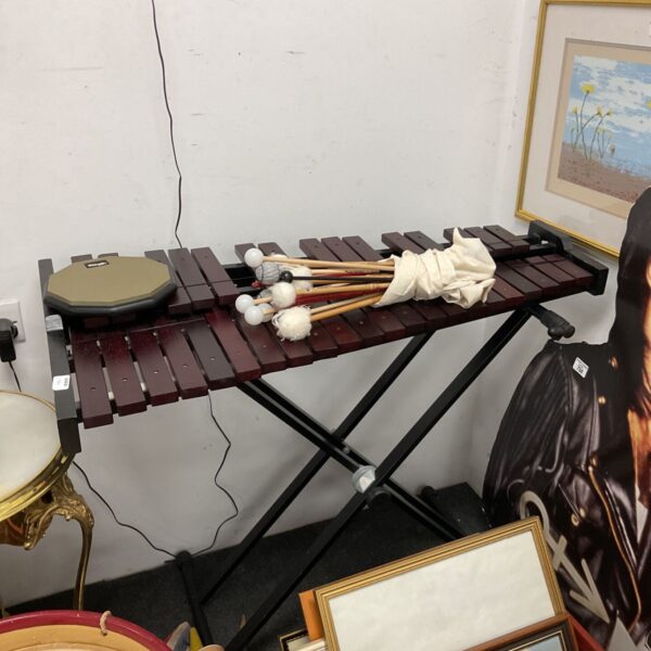 Large wooden xylophone on a stand with hammers and drum pad.