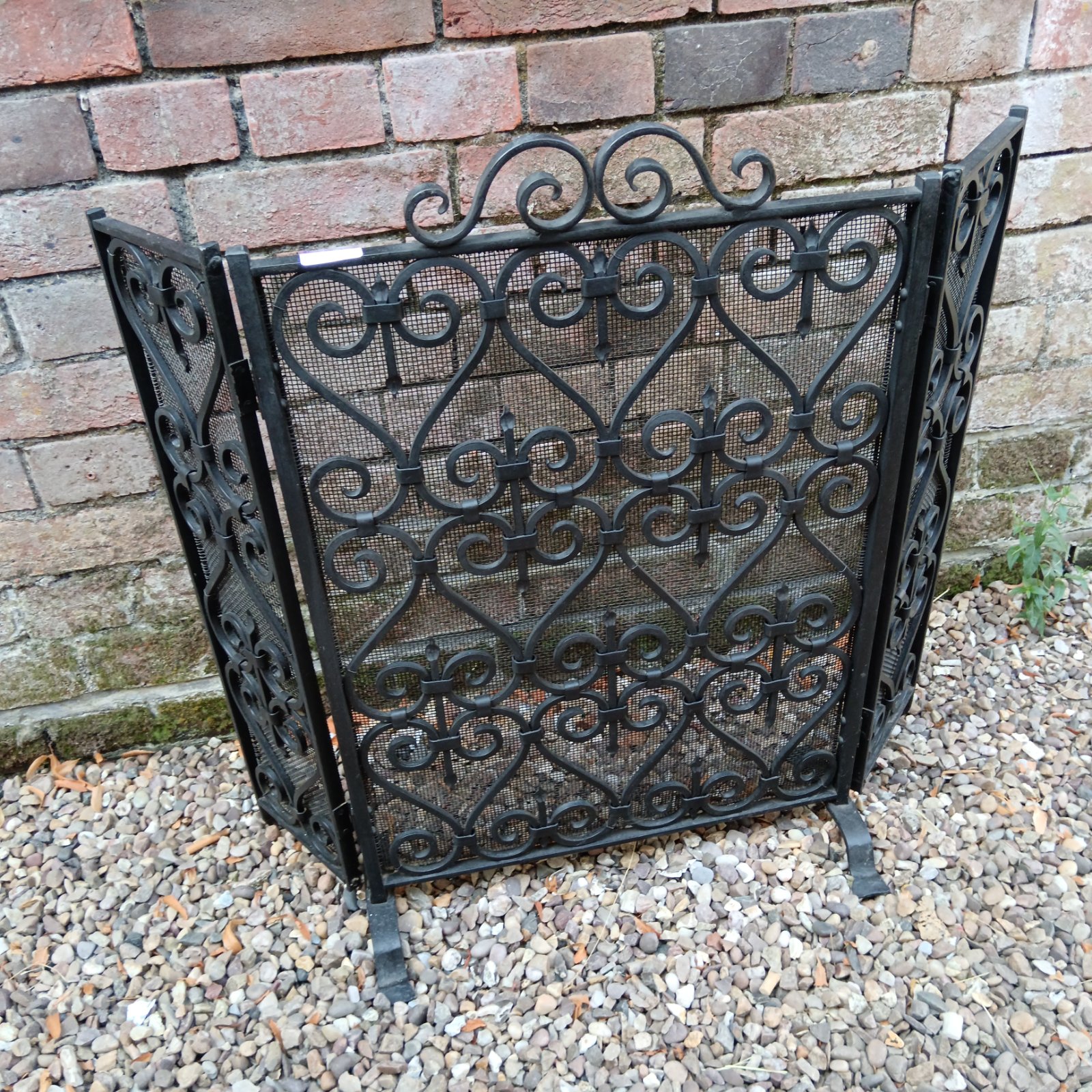 Antique wrought iron trifold fireplace screen with detailed design.