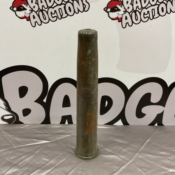 WW2 trench art shell, dated 1944, displayed against a backdrop.
