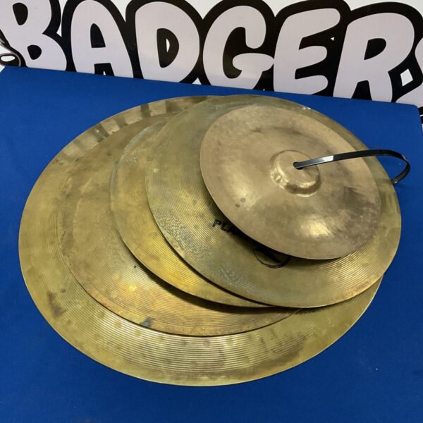 Stack of used Zildjian Planet Z cymbals on a blue surface.