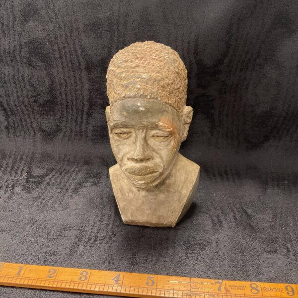 Close-up of hand-carved African stone head bust with ruler.