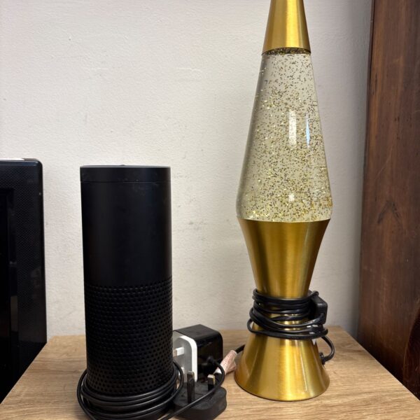 Amazon Echo first generation smart speaker with gold glitter lamp.