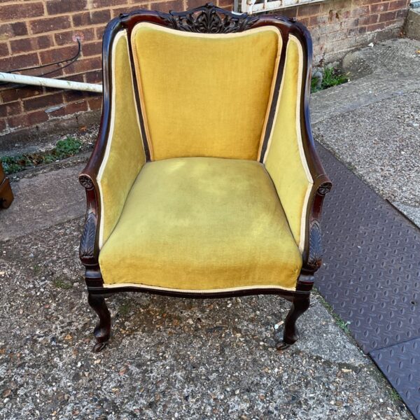 Antique carved walnut winged armchair with yellow upholstery.