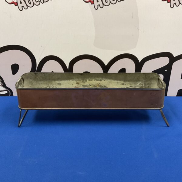 Antique copper sterilising trough on blue surface.