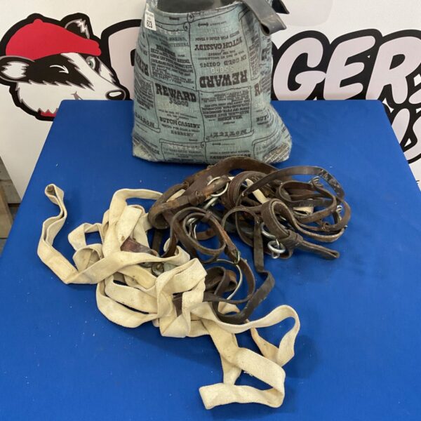 Antique horse tack lot featuring worn leather bridle and stirrups.