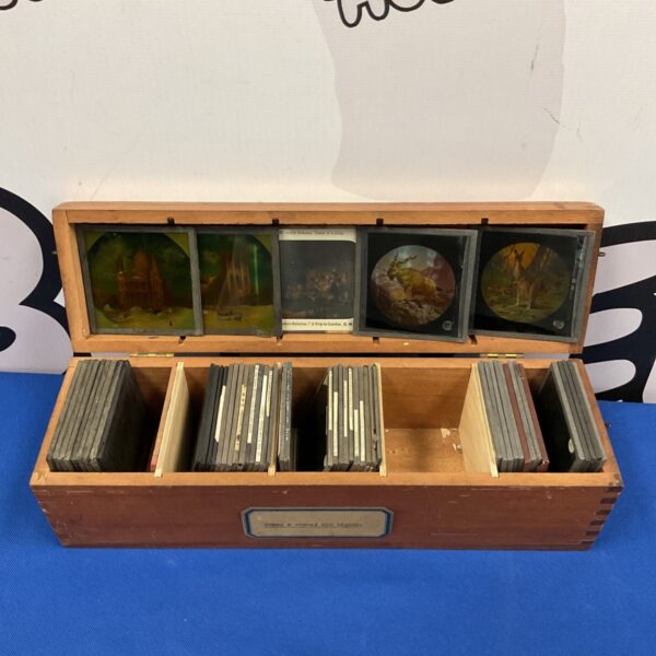 Antique magic lantern slides in a wooden storage case.