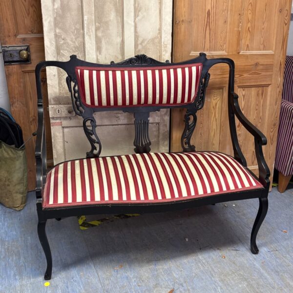 Antique mahogany parlour settee with red striped upholstery.