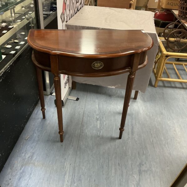 Antique mahogany side table with rounded half-moon shape.