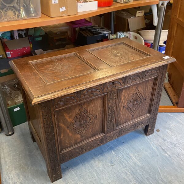 Antique carved oak blanket chest with detailed floral designs.