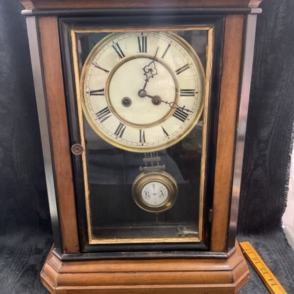 Antique oak cabinet clock with Roman numeral dial and key.