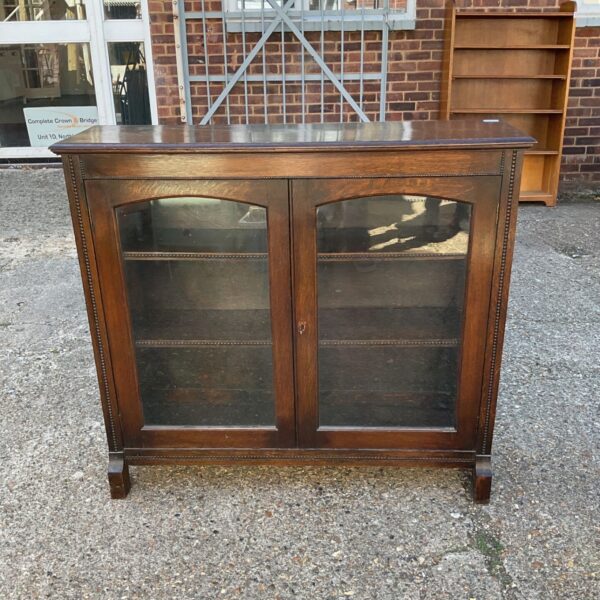 Antique oak display cabinet with glazed doors and beaded trim.