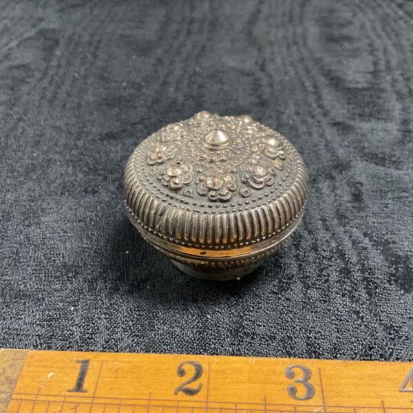 Close-up of antique silver trinket box with floral details.