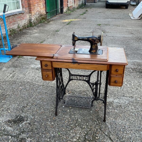 Antique Singer treadle sewing machine on wooden base.