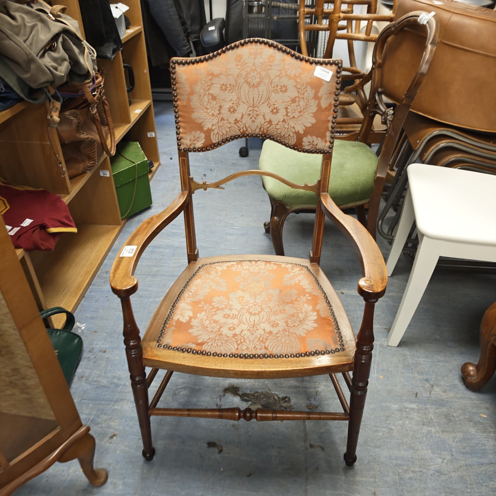 Antique wooden armchair with peach and gold damask upholstery and brass nailhead trim.