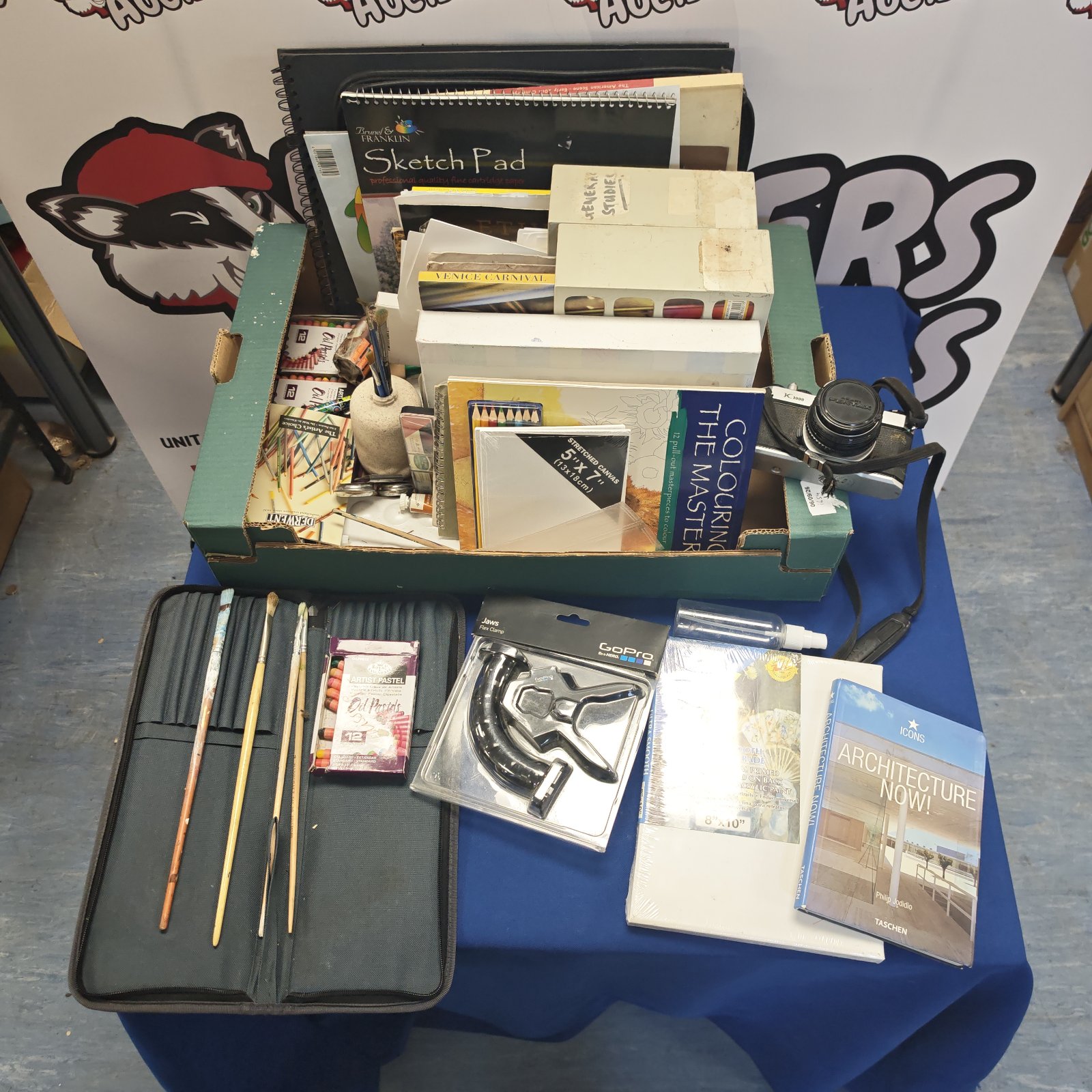 Mixed art supplies tray with pastels, brushes, and art books.