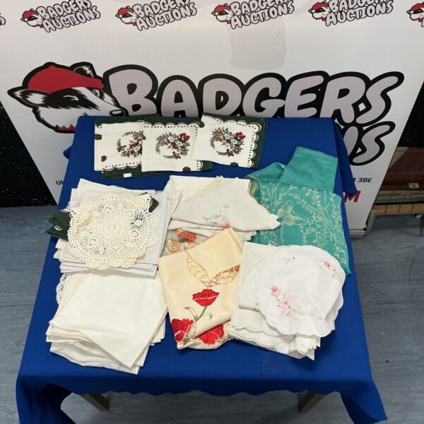 Assorted vintage tablecloths with embroidered details on a blue background.