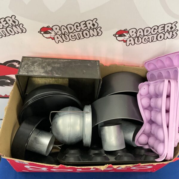 Assorted metal baking trays and dishes in a cardboard box.