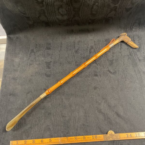 Antique bamboo shoe horn with greyhound head handle, full view.