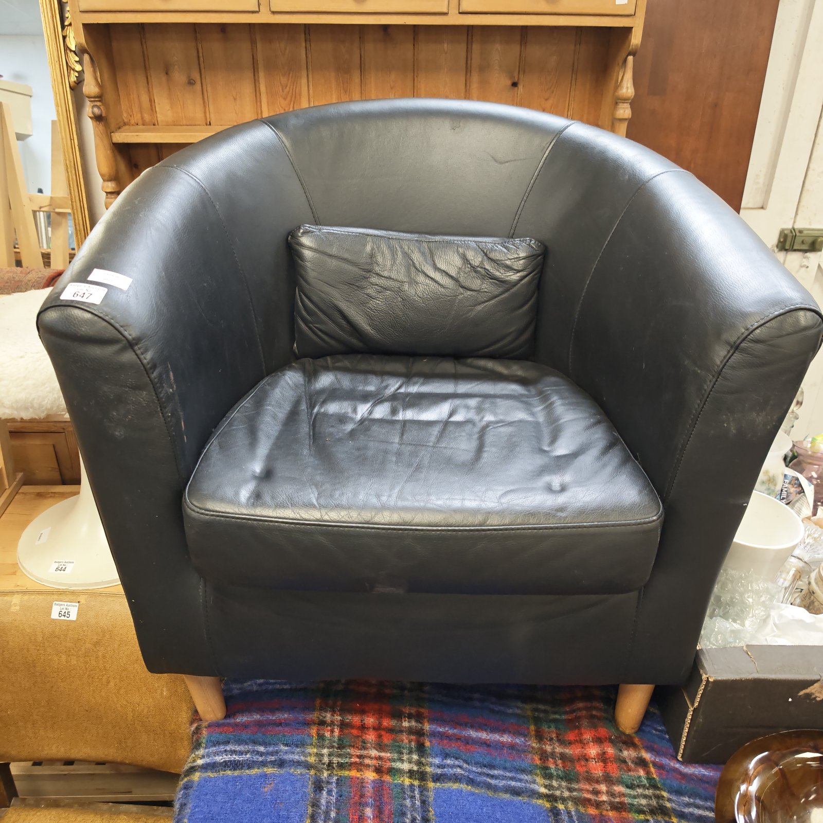 Black leather tub chair with wooden legs, vintage style seating.