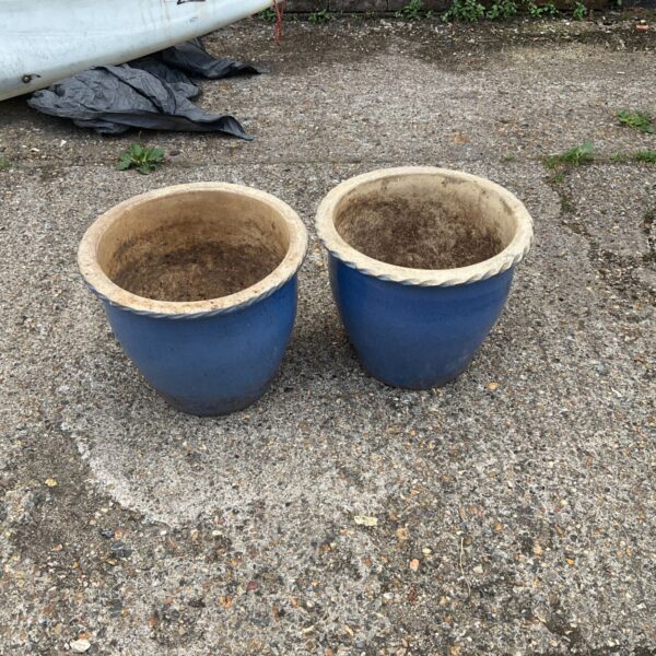 Pair of blue glazed garden planters in a garden setting.