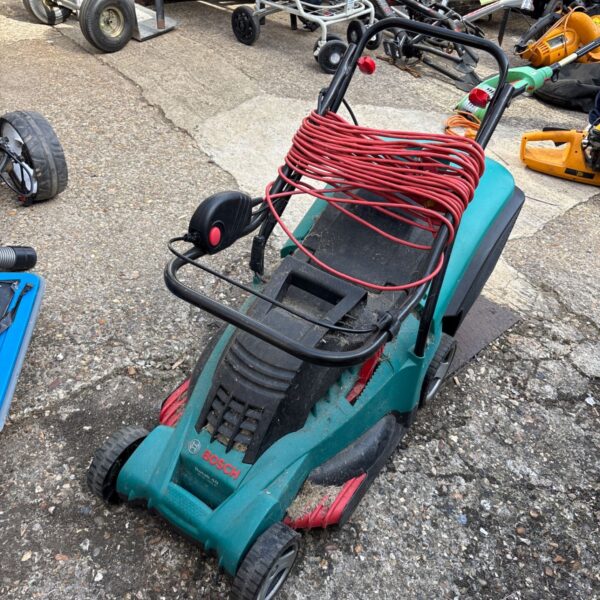 Green Bosch electric lawn mower in a garden setting.