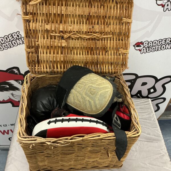 Vintage boxing training kit in a wicker basket with gloves and punch bag.