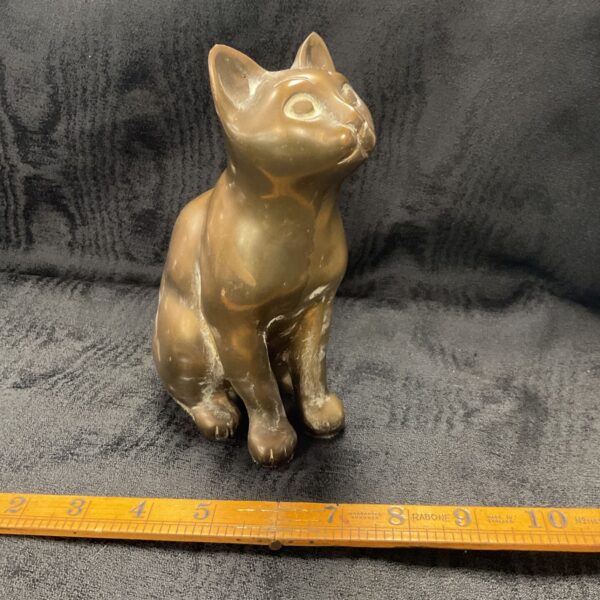 Vintage brass cat statue on a dark surface.