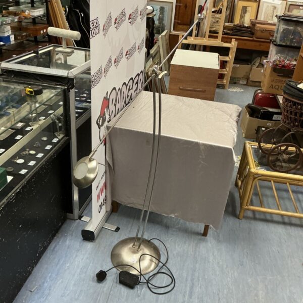 Brushed steel standard lamp with adjustable arm in a vintage setting.