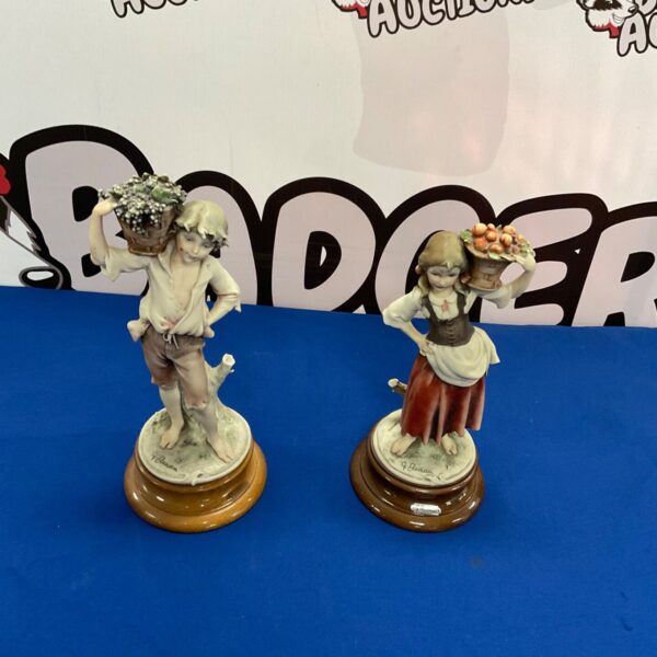 Antique Capodimonte figurines of a shepherd and shepherdess in detailed porcelain.