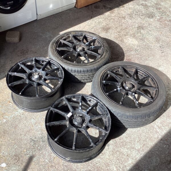 Dark grey car wheels requiring refurbishment for vehicle restoration.